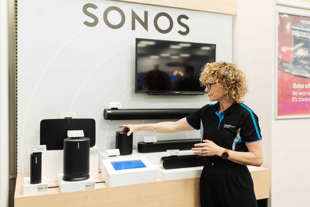 Brand ambassador in an electronics shop, providing demonstrations to potential customers seeking more information. 