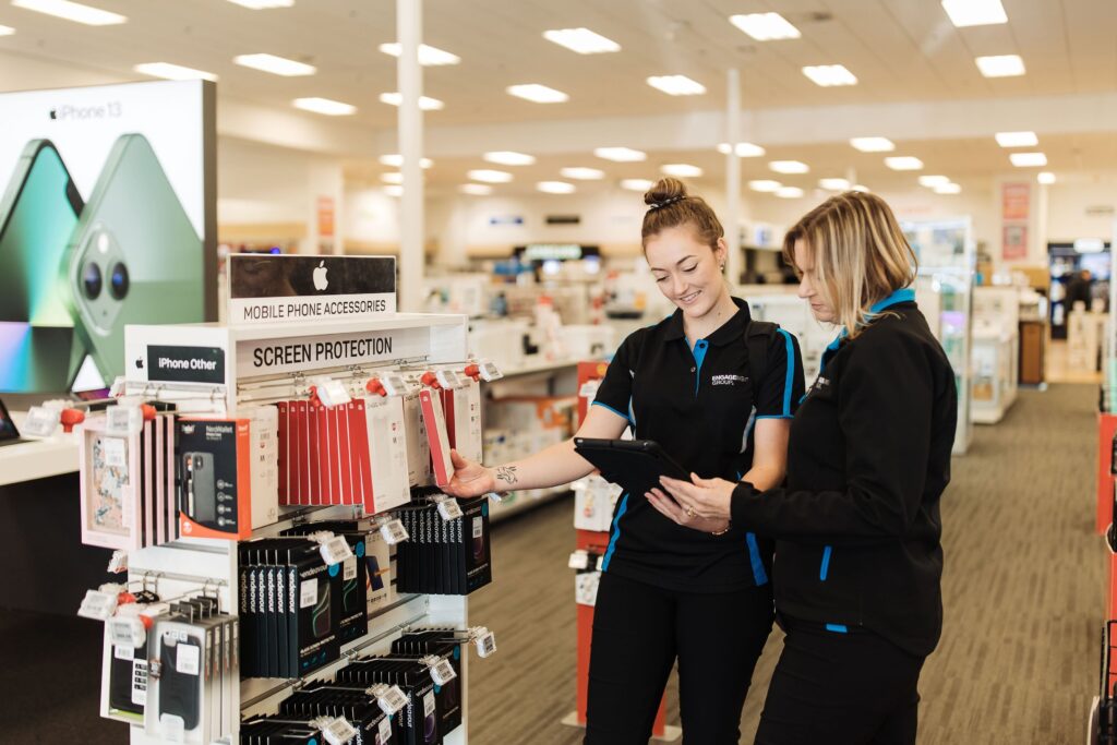 Engagement Group merchandisers discussing stock replenishment strategies on a tablet in a store, ensuring optimal product availability.