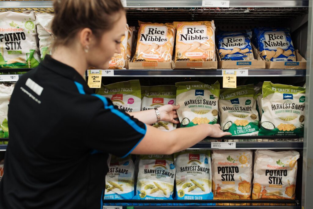 Merchandiser restocking shelves with Harvest Snaps and other snacks, preventing stockouts and ensuring a seamless shopping experience.