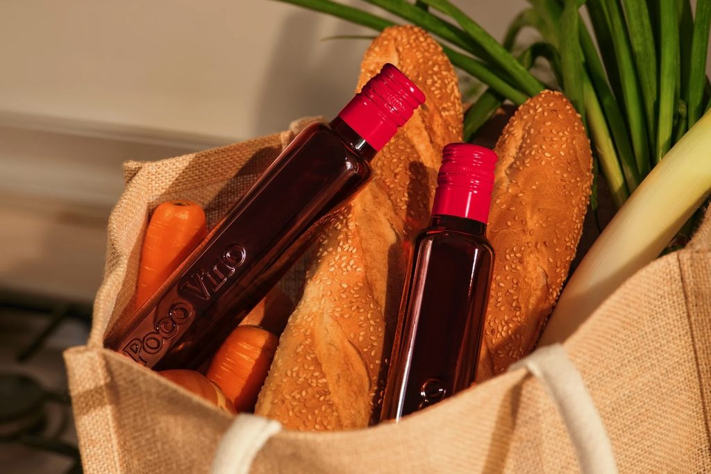 Two bottles of PocoVino shiraz in a bag with some baguettes.